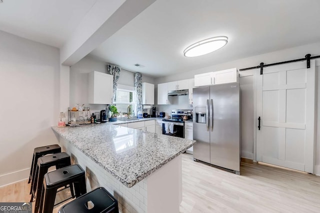 kitchen with stainless steel appliances, a barn door, a sink, a peninsula, and under cabinet range hood