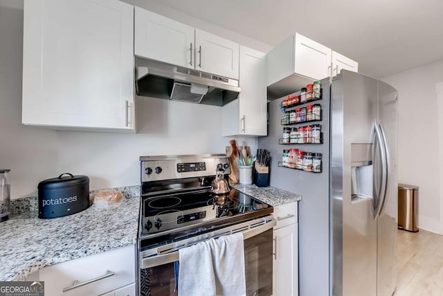 kitchen with light stone counters, under cabinet range hood, white cabinetry, appliances with stainless steel finishes, and light wood finished floors