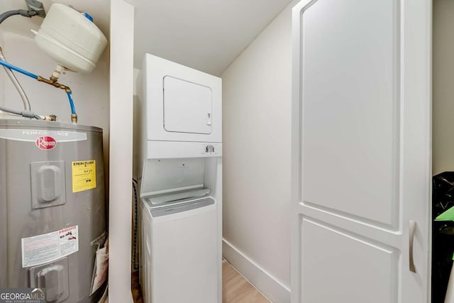 laundry room featuring laundry area, baseboards, stacked washer / drying machine, light wood-type flooring, and water heater