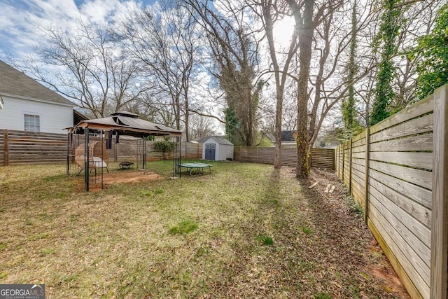 view of yard featuring a gazebo, an outbuilding, a fenced backyard, and a storage shed