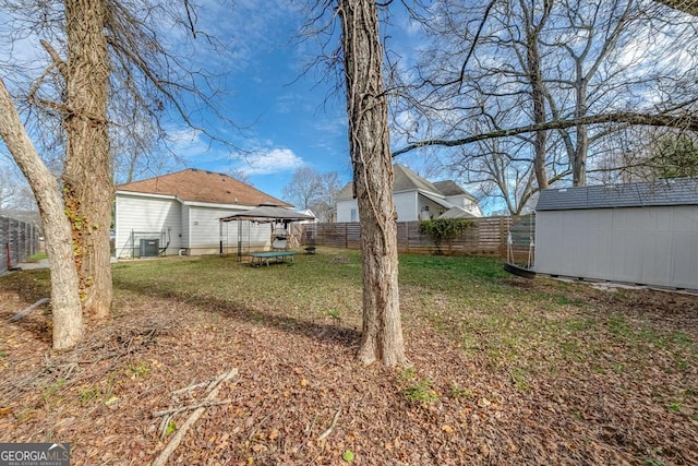 view of yard featuring cooling unit, a fenced backyard, an outdoor structure, and a storage unit