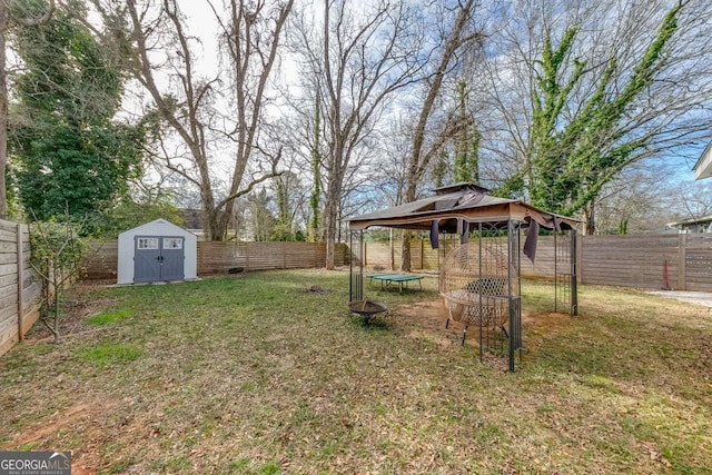 view of yard featuring an outdoor fire pit, a fenced backyard, a gazebo, a shed, and an outdoor structure