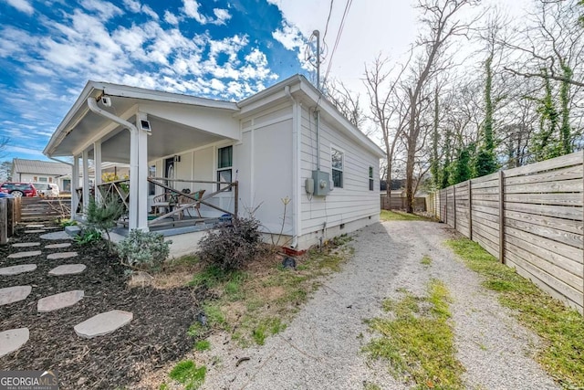 view of side of property featuring a porch, crawl space, driveway, and fence