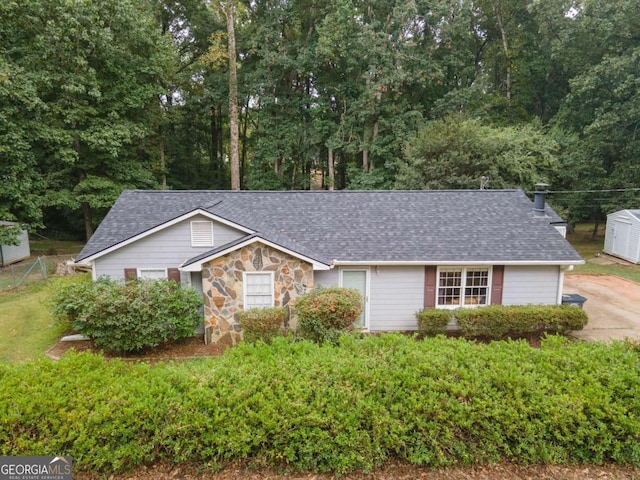 single story home featuring stone siding and roof with shingles