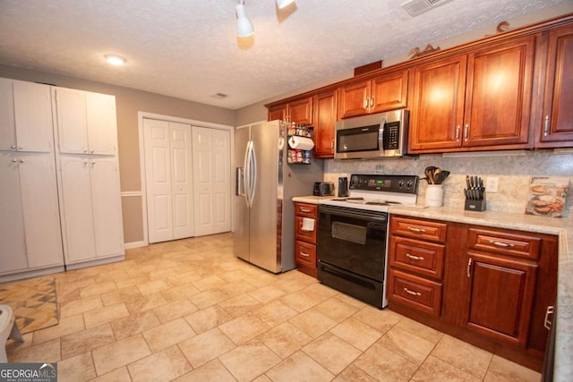 kitchen with visible vents, brown cabinetry, appliances with stainless steel finishes, light countertops, and backsplash