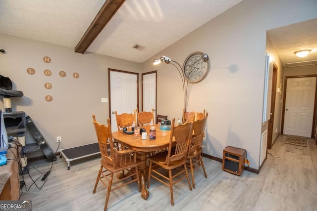 dining room with baseboards, visible vents, lofted ceiling with beams, light wood-style flooring, and a textured ceiling