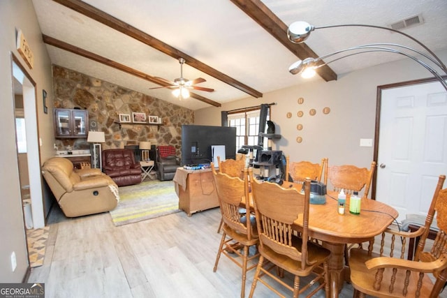 dining space featuring lofted ceiling with beams, light wood finished floors, visible vents, and a ceiling fan