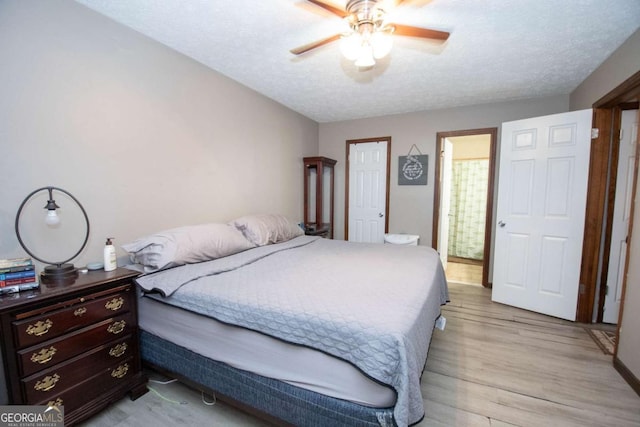 bedroom with light wood-type flooring, ceiling fan, a textured ceiling, and ensuite bath