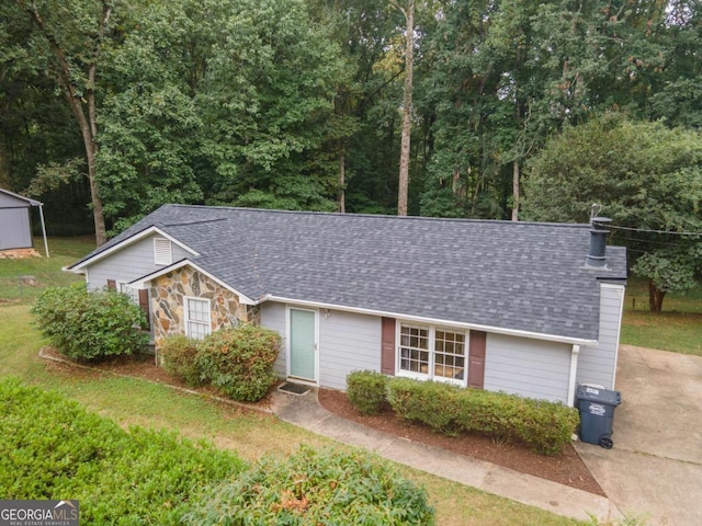 ranch-style house with stone siding, a shingled roof, a chimney, and a front yard