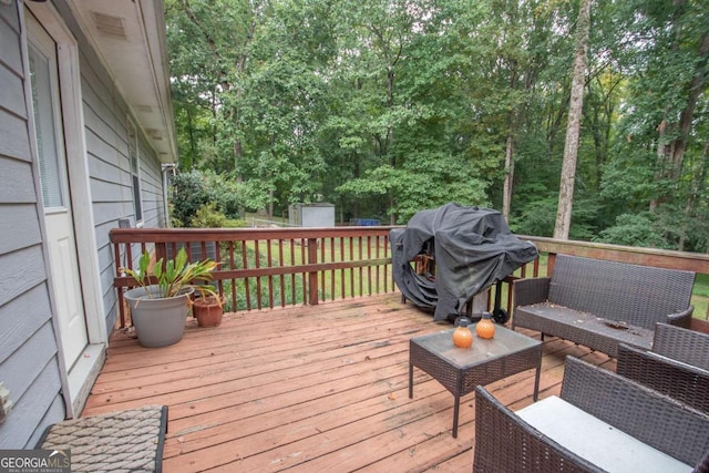 deck with an outbuilding, a storage shed, outdoor lounge area, and a grill