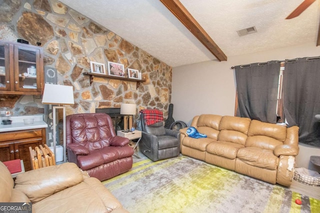 living area featuring lofted ceiling with beams, a fireplace, visible vents, and a textured ceiling