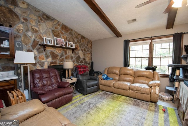 living area featuring visible vents, a ceiling fan, lofted ceiling with beams, a textured ceiling, and a fireplace