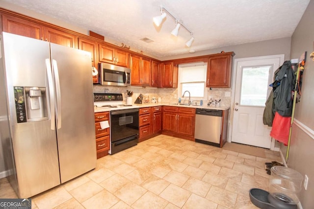 kitchen featuring decorative backsplash, appliances with stainless steel finishes, light countertops, a textured ceiling, and a sink