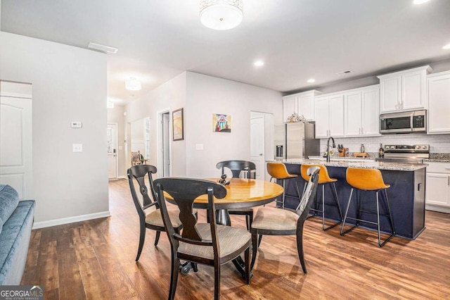 dining room featuring dark wood-style floors, recessed lighting, and baseboards