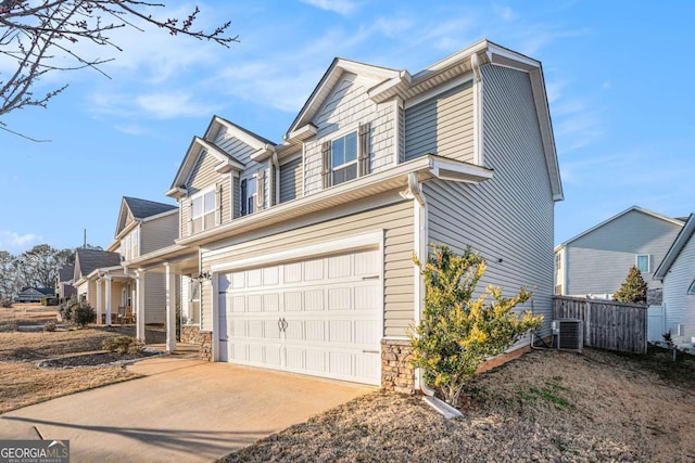 view of front of house with driveway, an attached garage, fence, and central AC