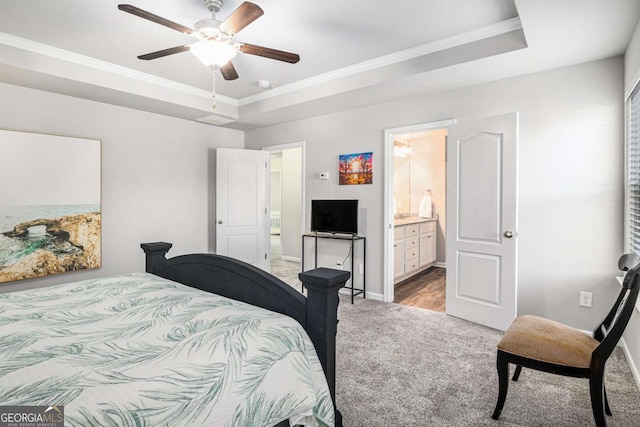 carpeted bedroom featuring ornamental molding, a raised ceiling, ensuite bath, and baseboards