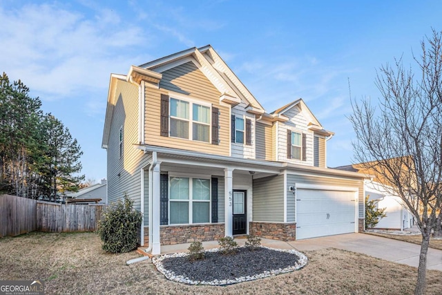 craftsman-style house featuring stone siding, concrete driveway, and fence