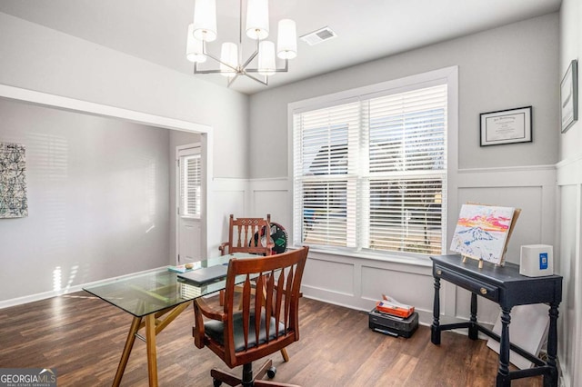 office space with a chandelier, wood finished floors, visible vents, and a decorative wall