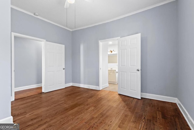 unfurnished bedroom featuring baseboards, a ceiling fan, ensuite bath, wood finished floors, and crown molding