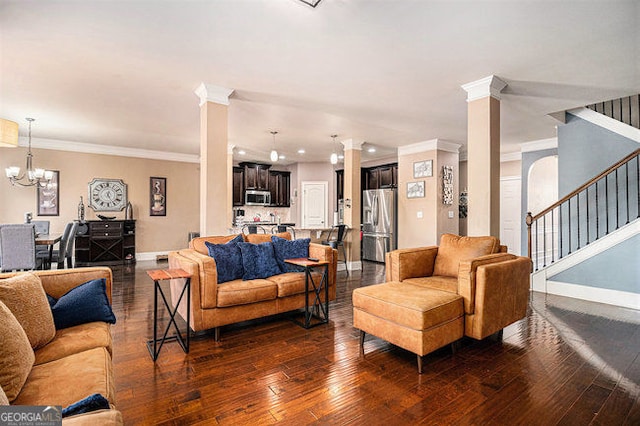 living room featuring baseboards, dark wood finished floors, stairs, ornate columns, and a notable chandelier