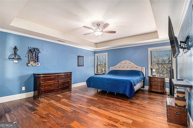 bedroom featuring a tray ceiling, baseboards, and wood finished floors