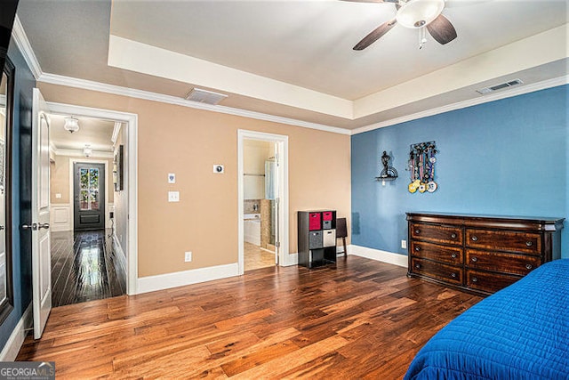 bedroom with wood finished floors, a raised ceiling, and visible vents