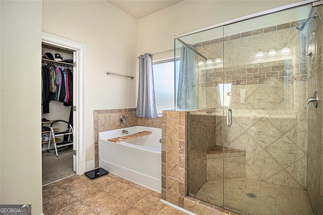 bathroom with a walk in closet, a bath, and a shower stall