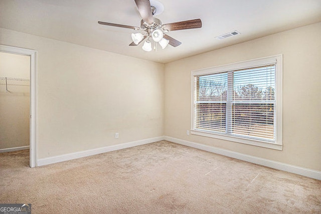 spare room with carpet, visible vents, ceiling fan, and baseboards