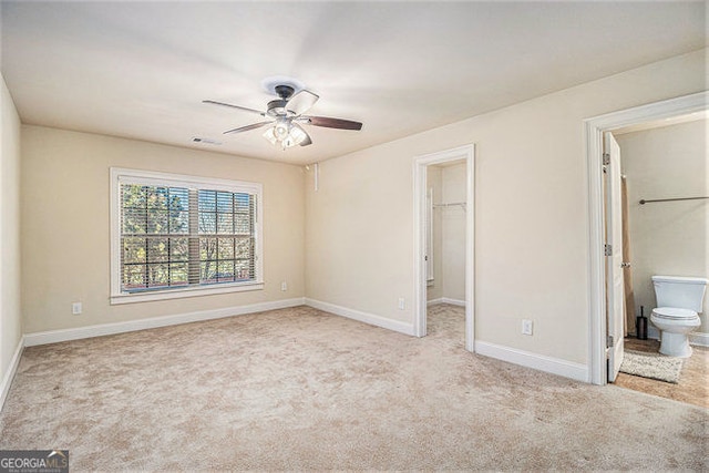 unfurnished bedroom featuring ensuite bathroom, baseboards, a spacious closet, a closet, and carpet