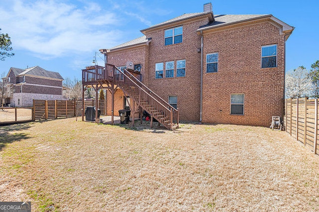 back of house featuring a fenced backyard, brick siding, a yard, stairway, and a chimney