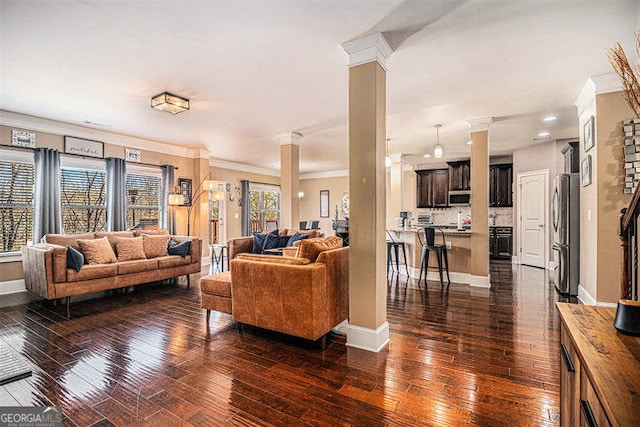 living area featuring crown molding, dark wood-style flooring, decorative columns, and baseboards