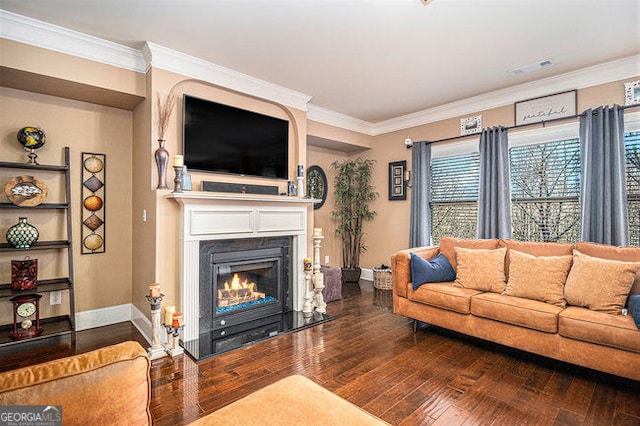 living area featuring baseboards, a glass covered fireplace, hardwood / wood-style flooring, and crown molding