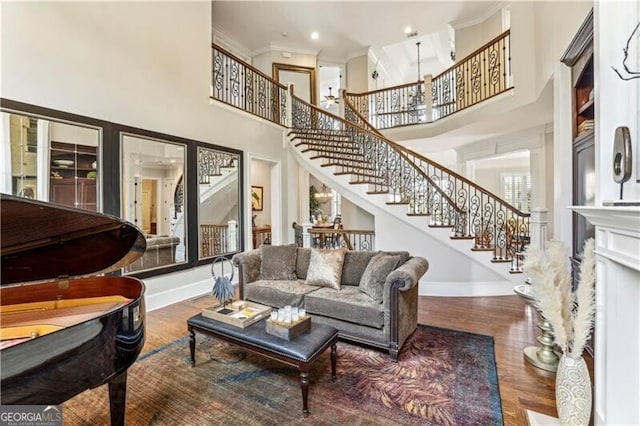 living area featuring crown molding, stairway, baseboards, and wood finished floors