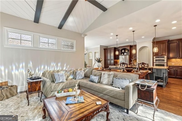 living room with vaulted ceiling with beams, wood finished floors, plenty of natural light, and arched walkways