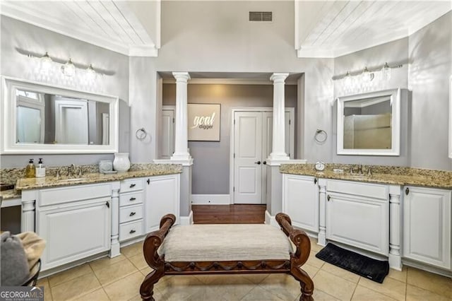 bathroom with decorative columns, two vanities, ornamental molding, a sink, and tile patterned floors