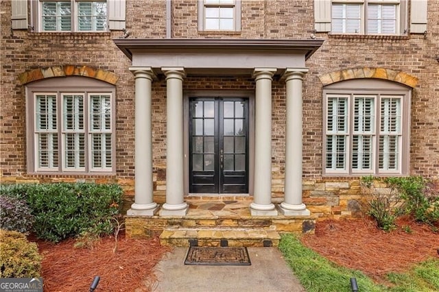 property entrance featuring french doors and brick siding