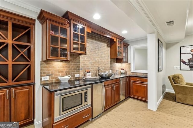 kitchen featuring visible vents, glass insert cabinets, ornamental molding, stainless steel appliances, and backsplash