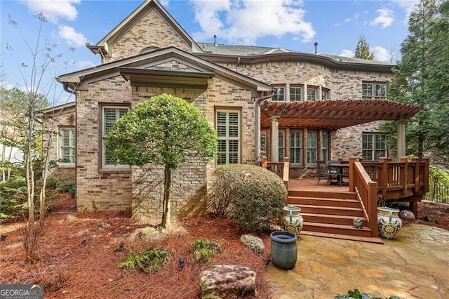 rear view of house featuring a deck, brick siding, and a pergola