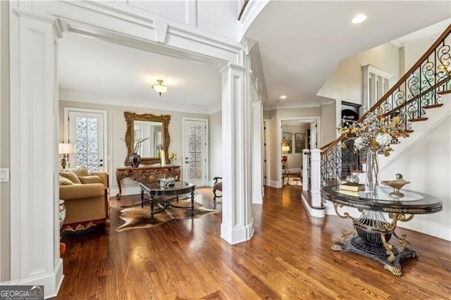 entryway with stairs, crown molding, ornate columns, and wood finished floors