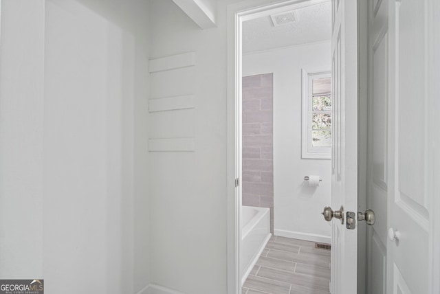 full bathroom with a textured ceiling, wood finish floors, visible vents, and baseboards