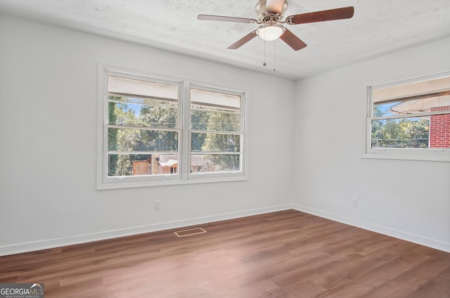 unfurnished room featuring visible vents, ceiling fan, a textured ceiling, wood finished floors, and baseboards