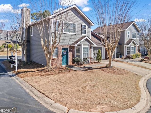 view of front of house with driveway, a chimney, and brick siding