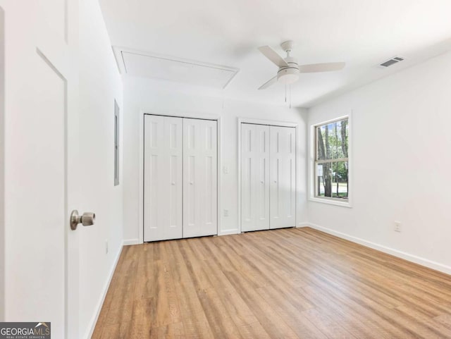 8087 Beachwood Dr, Murrayville, GA 30564 - unfurnished bedroom featuring attic access, visible vents, baseboards, light wood-style floors, and two closets
