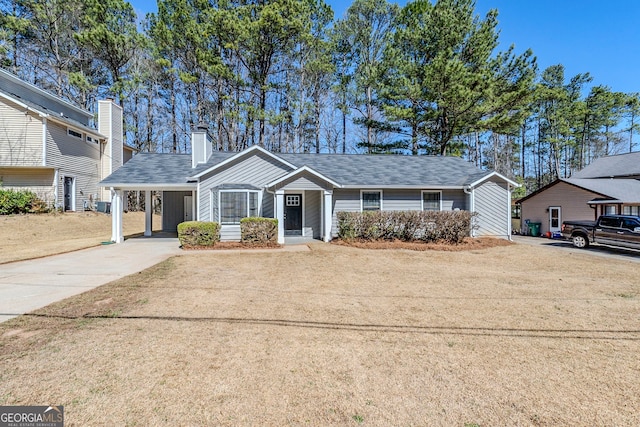 ranch-style home with an attached carport, concrete driveway, and a chimney