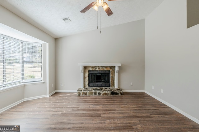 unfurnished living room with visible vents, a ceiling fan, wood finished floors, a textured ceiling, and a fireplace