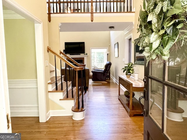 interior space featuring stairs, a towering ceiling, baseboards, and wood finished floors