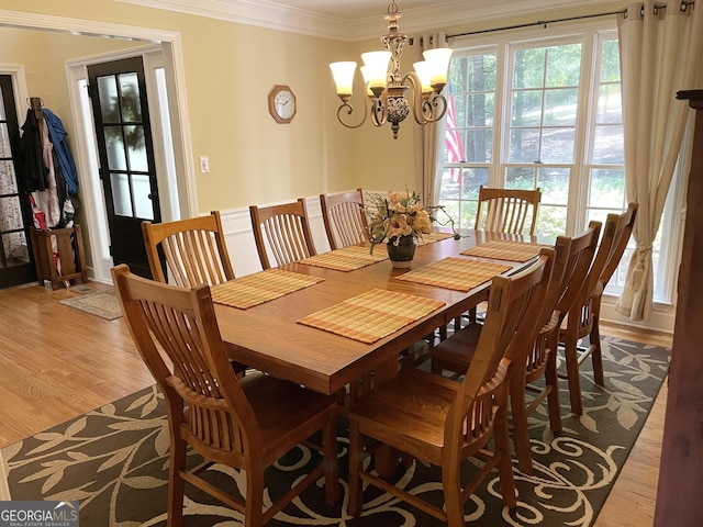 dining room featuring light wood-style floors, an inviting chandelier, and crown molding