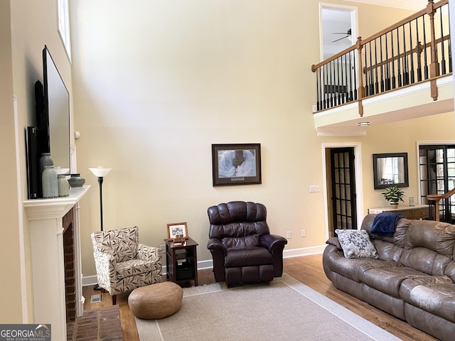 living area with a towering ceiling, baseboards, and wood finished floors