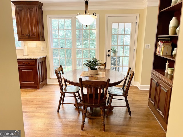 dining space with ornamental molding, a healthy amount of sunlight, light wood-style floors, and baseboards