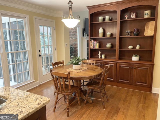 dining room with light wood-type flooring and crown molding